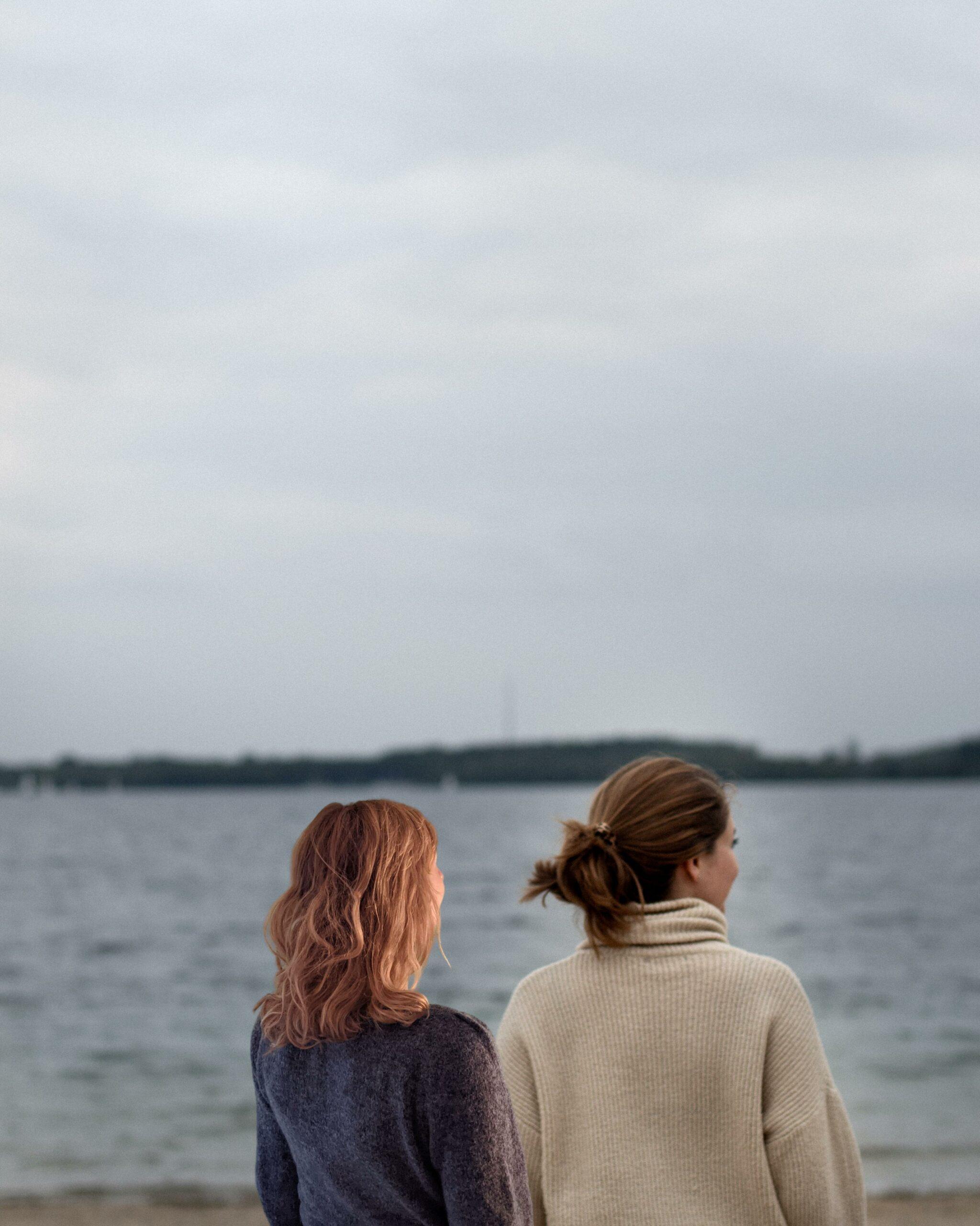 Das Bild zeigt Anya und Fine von True Good Things. Die beiden Frauen schauen auf einen See hinaus.