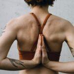 Das Bild eine Frau von hinten mit verschränkten Händen in der Yoga Pose Namaste.