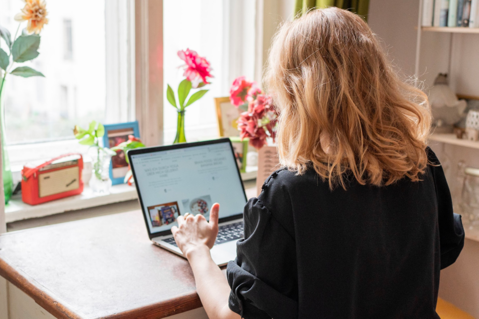 Das Bild zeigt eine junge Frau am Schreibtisch vor ihrem Laptop sitzend, die über berufliche Veränderung nachdenkt.
