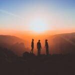 Das Bild zeigt drei Menschen vor einem Sonnenaufgang, der den Jahresbeginn symbolisiert.
