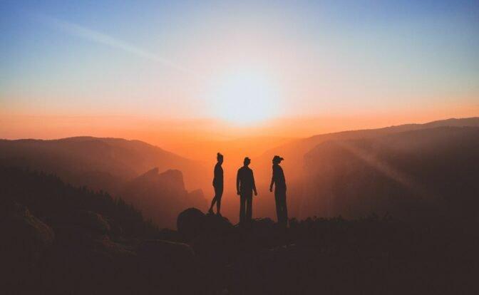 Das Bild zeigt drei Menschen vor einem Sonnenaufgang, der den Jahresbeginn symbolisiert.